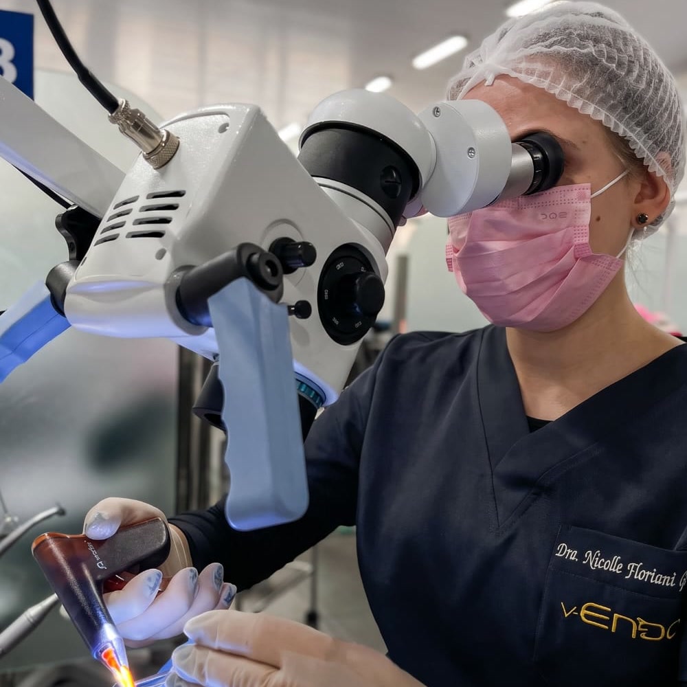 Dra. Nicolle Floriani Gerlach atendendo com o microscópio operatório